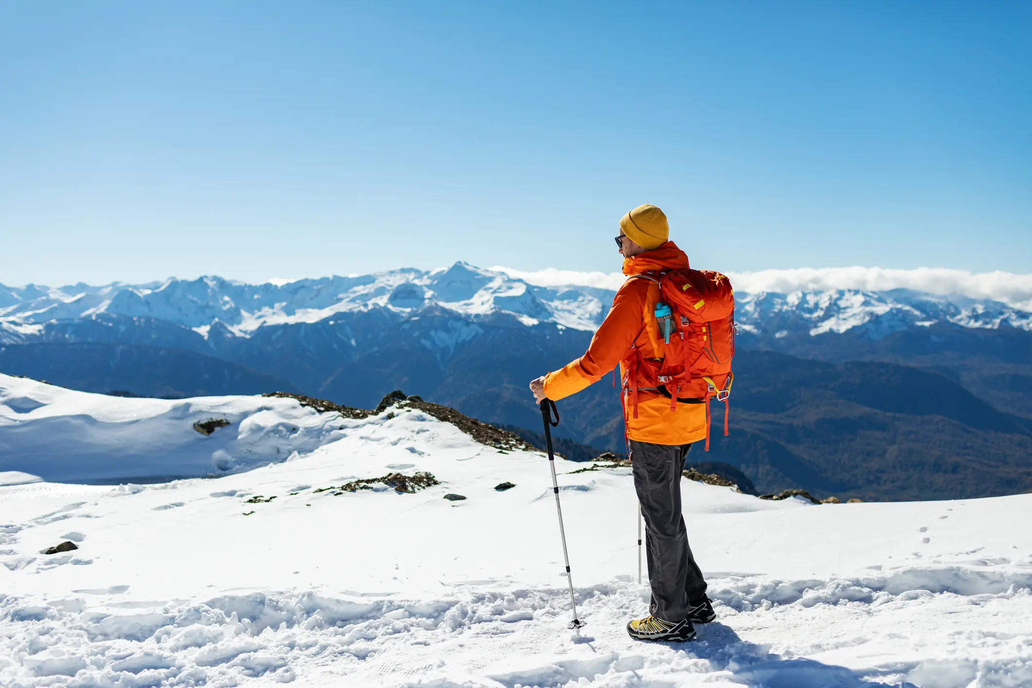 Hiker in orange jacket on snowy mountain lookout