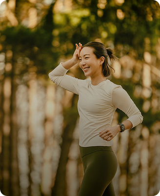 Smiling woman jogging outdoors in sunlit forest