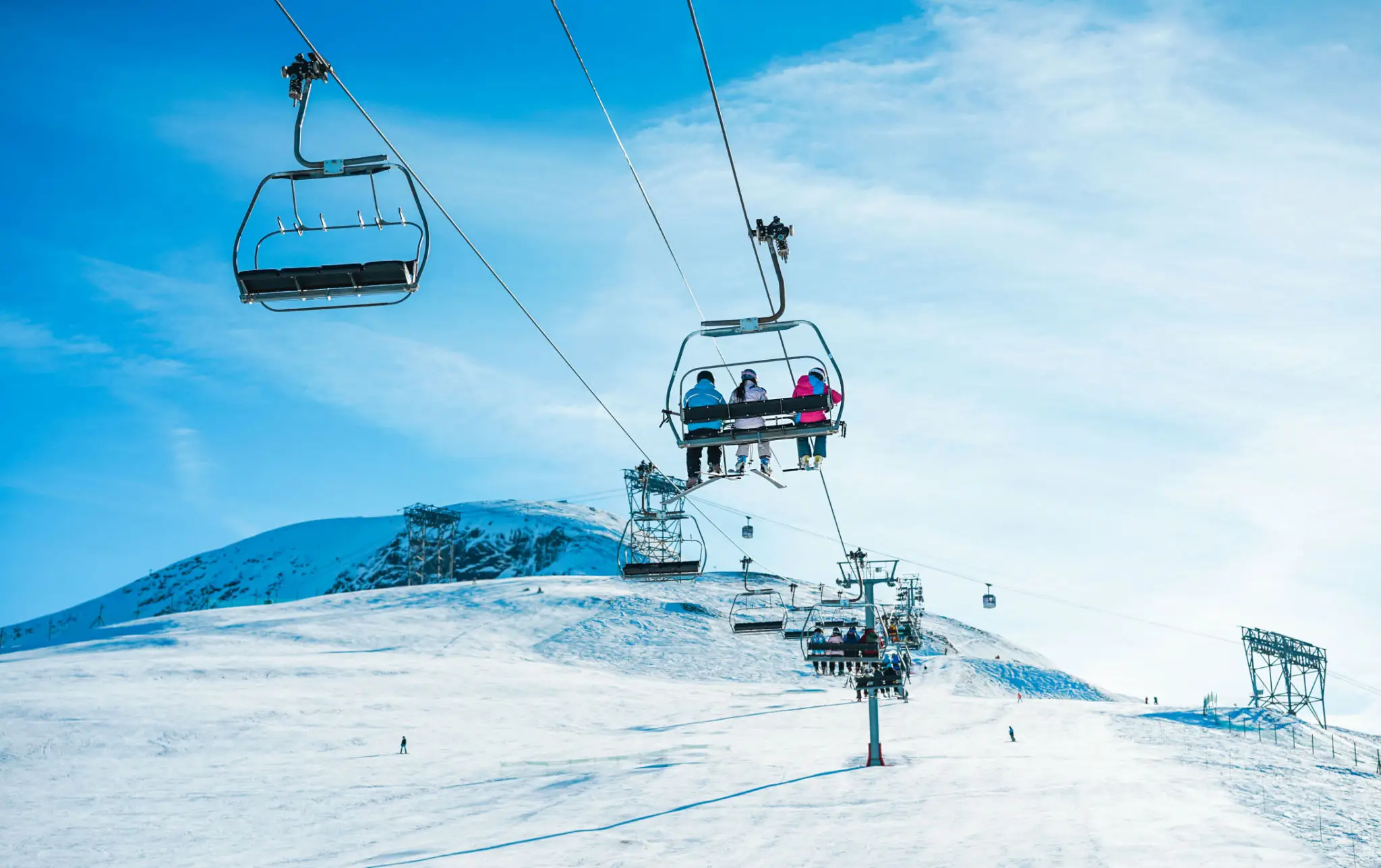 Chairlift with skiers over snowy mountain