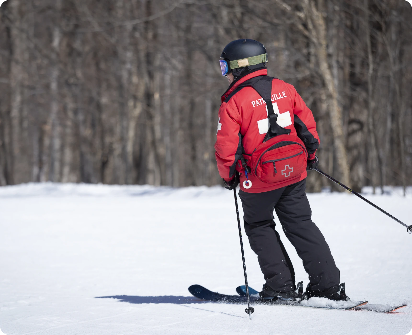 Ski patrol member skiing on snowy slope.