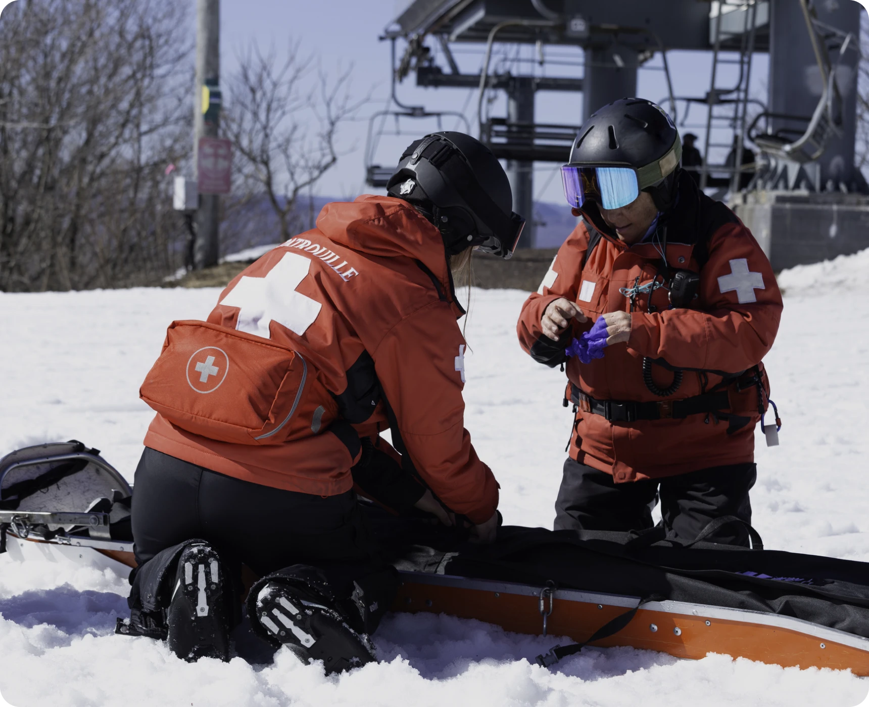 Ski patrollers assisting in snowy mountain setting.